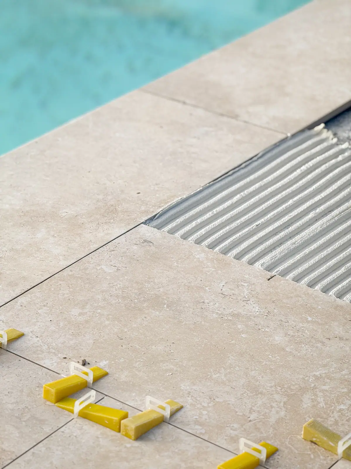 Pose d'une plage de piscine : colle peignée et calage