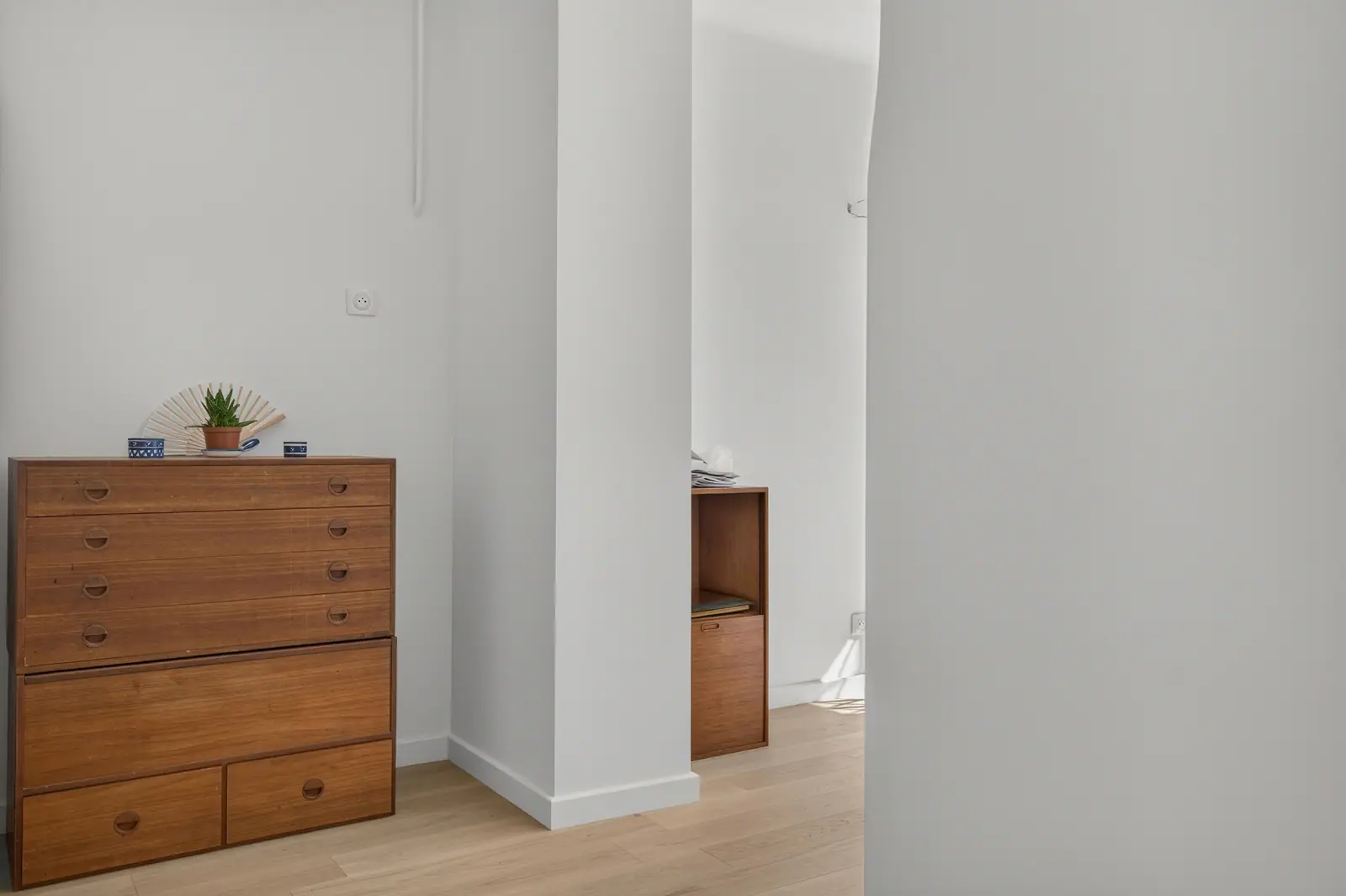 Couloir aux murs blancs et commode en bois