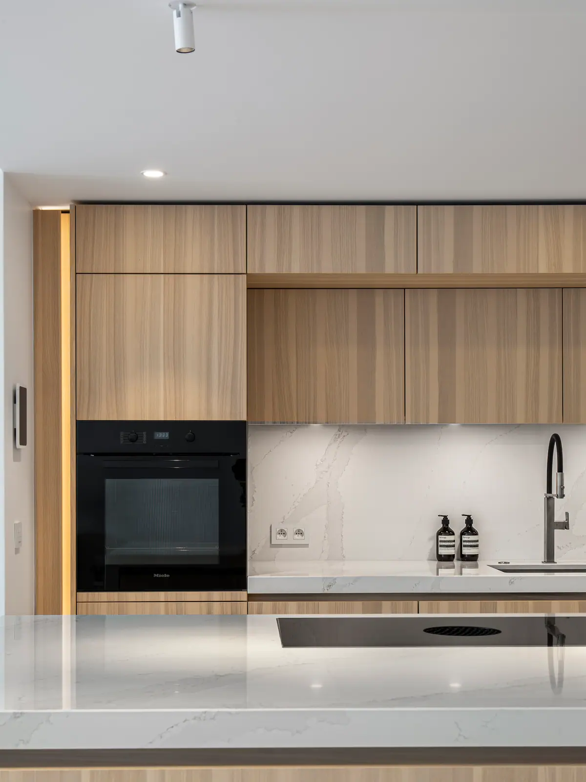 Façades de cuisine en bois clair, four encastré et crédence effet marbre