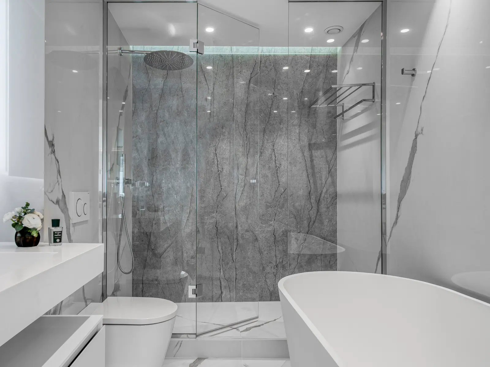 Salle de bains avec douche en grandes plaques effet marbre gris et baignoire îlot