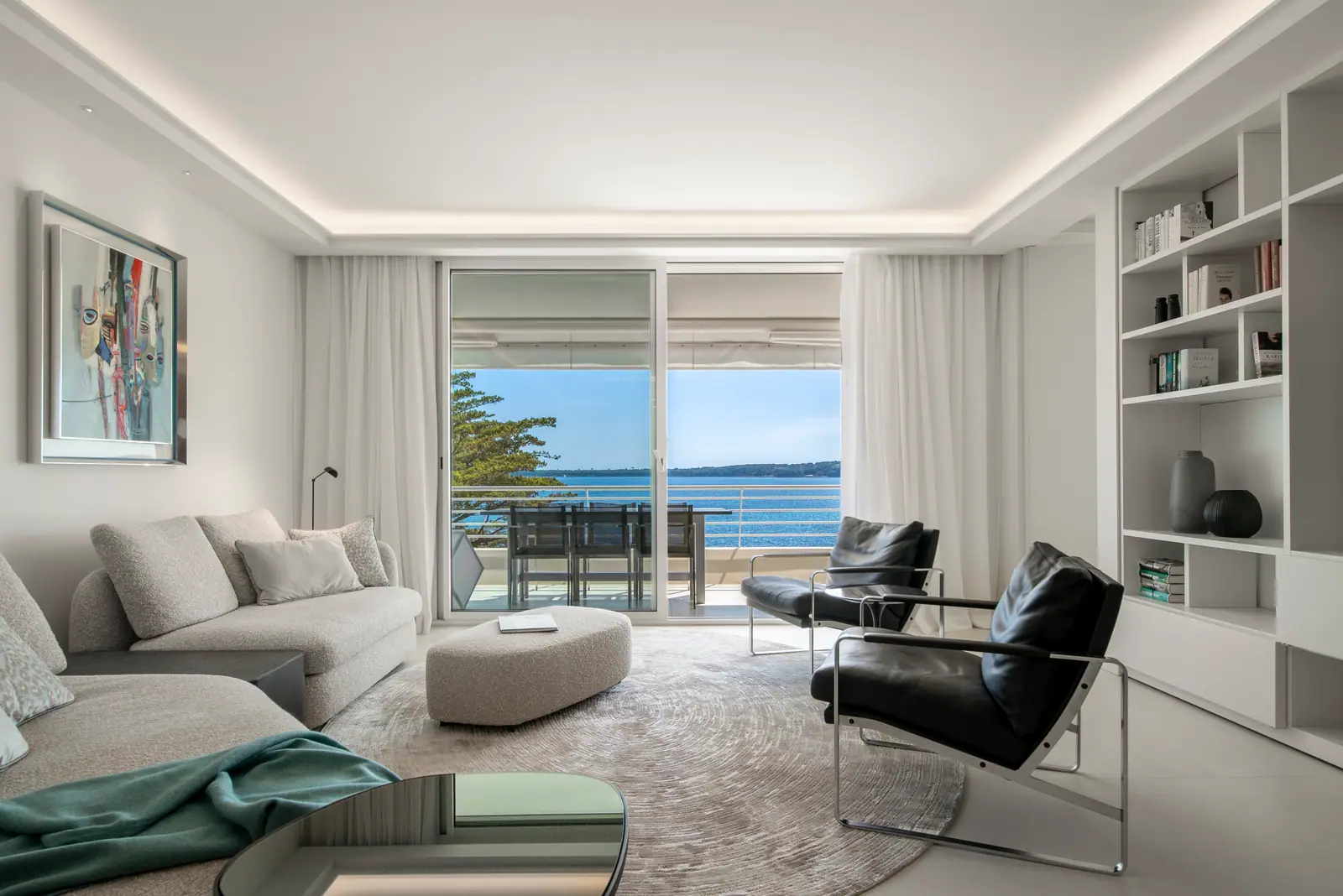 Salon lumineux avec bibliothèque intégrée et baie vitrée sur la mer