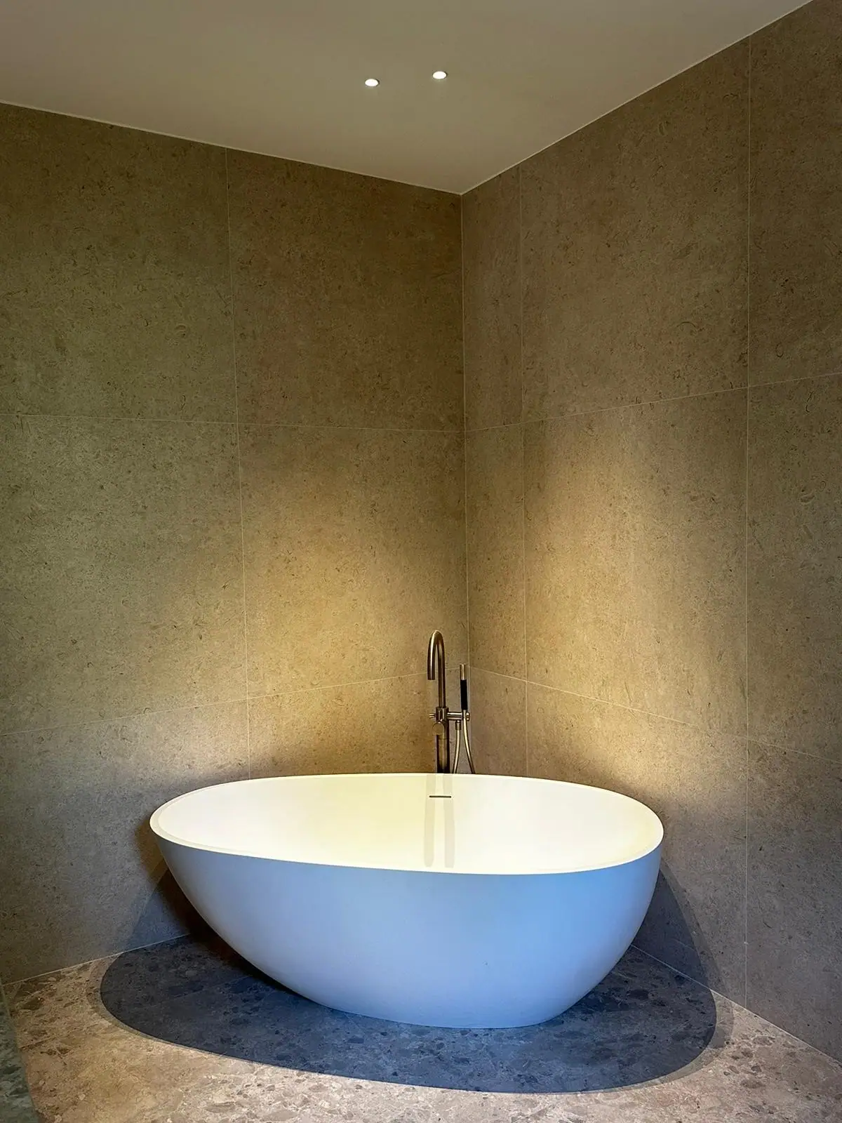 Baignoire îlot dans une salle de bains en revêtement effet pierre