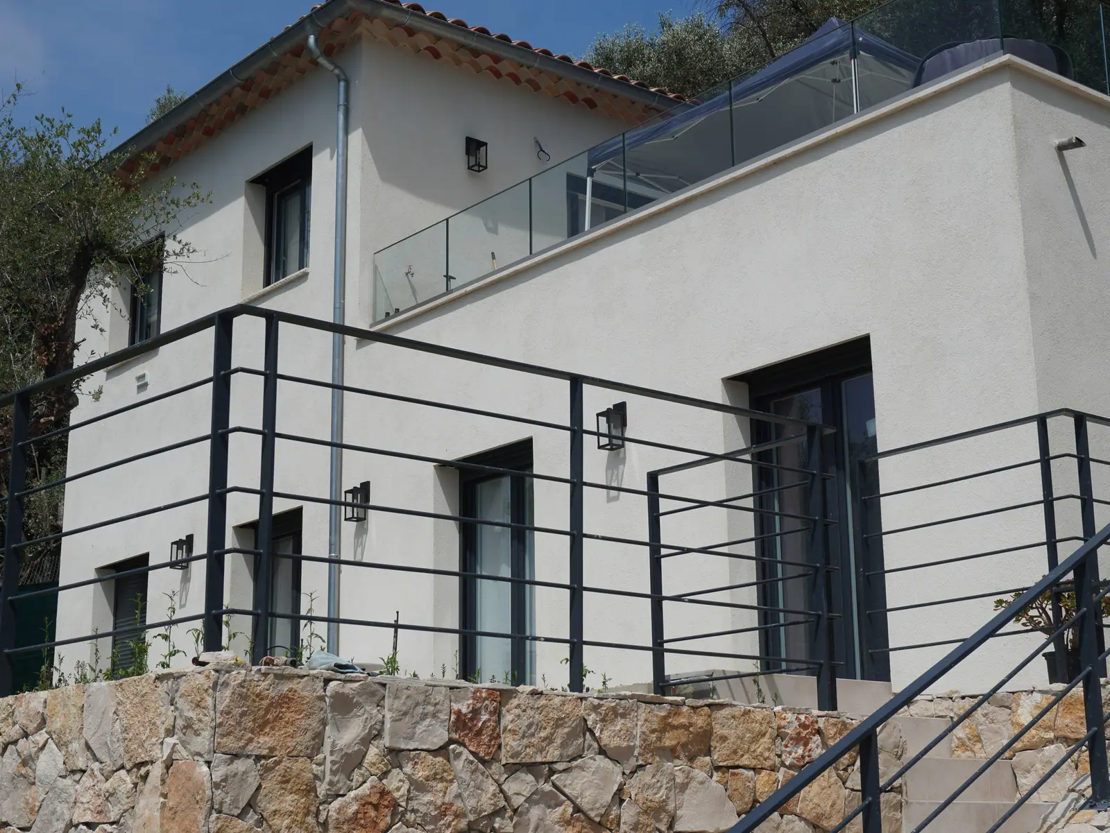 Villa neuve sur terrain en pente, mur de soutènement en pierre et garde-corps