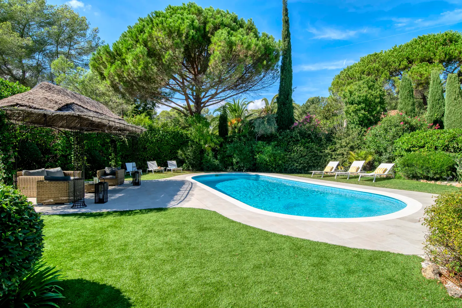 Piscine et sa plage dans un jardin arboré